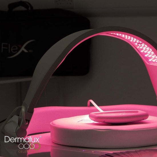 Pink LED light therapy device with 'Dermalux' branding on a dark background