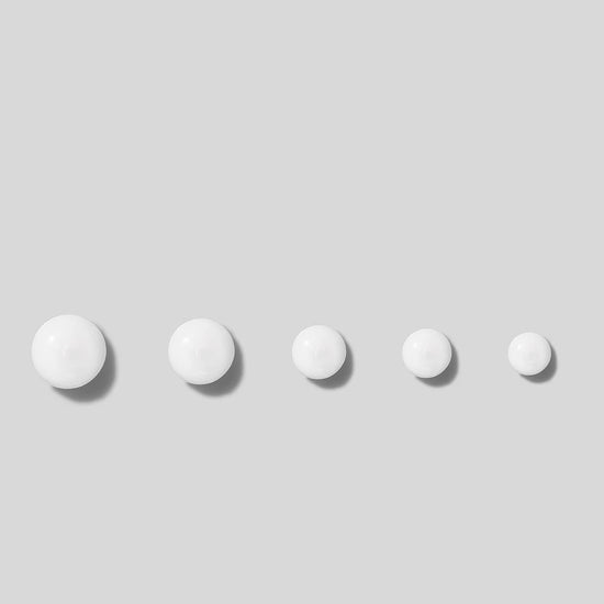 Five white drops of cream on a light gray background