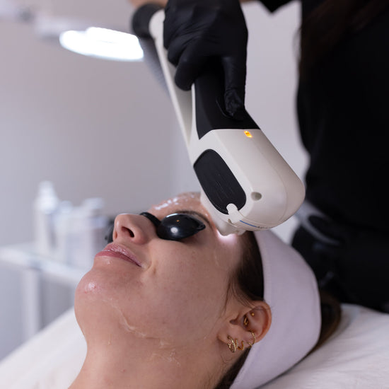 Person receiving a light treatment on their face in a clinical setting.