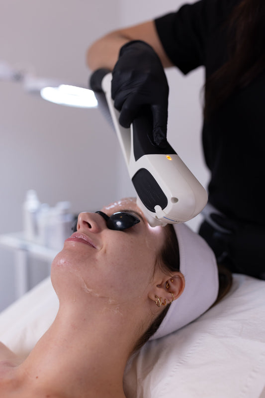 Person receiving a light treatment on their face in a clinical setting.