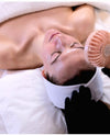 Person receiving a facial treatment with a small fan and towel in the background