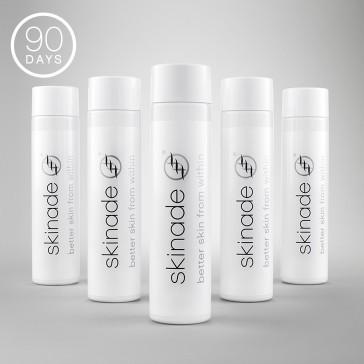 Set of white skincare bottles with 'skinade' branding on a gray background
