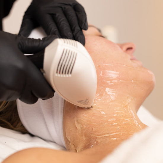 Person receiving a facial treatment with a device held by gloved hands.